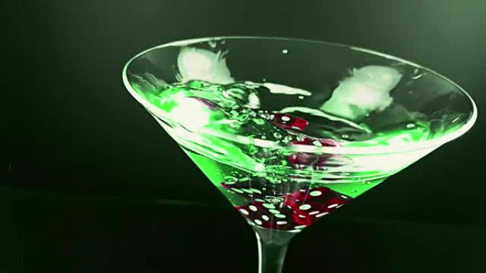 红色骰子掉落，飞溅成蓝色新鲜酒精鸡尾酒酒杯在绿色灯光背景下，拍摄慢动作，娱乐和休闲娱乐赌场游戏