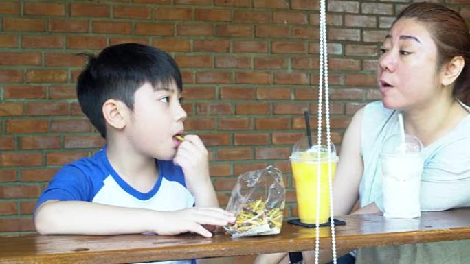 快乐的亚洲妈妈和她的儿子一起吃零食和玩耍