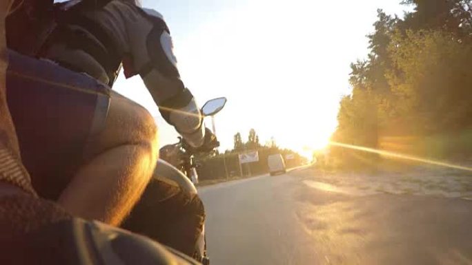 日落时，两名男子在乡村公路上高速骑摩托车。朋友们骑着自行车高速走向太阳。低视角视点特写