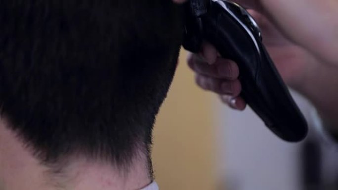 理发师在理发店用电动剃须刀塑造发型白人，特写。