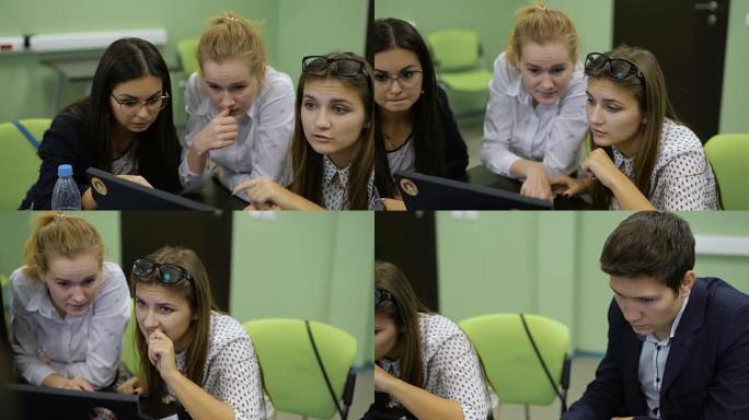 年轻的男女学生坐在办公桌前，与PC一起工作，看着显示器，讨论并准备为观众介绍他们的启动项目。三个年轻