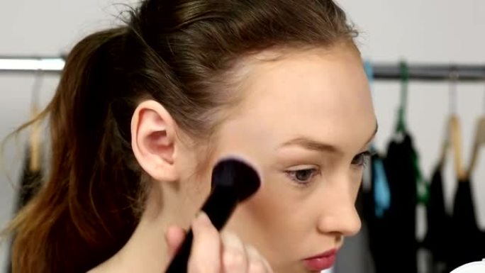 年轻美丽透明清洁护肤健康女人用化妆粉眼影，刷遮光在脸上
