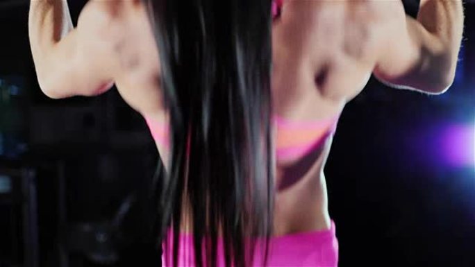 运动的女人训练背部的肌肉。健身房里的引体向上。女性健美