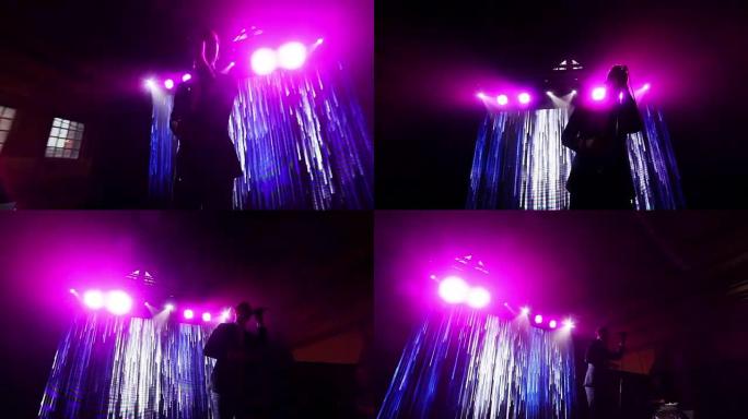 剪影男子在夜总会音乐会舞台上的LED屏幕背景下唱歌，显示缓慢移动的瀑布线POV的抽象动画。时尚歌手在