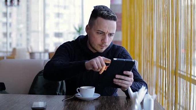 带平板电脑的年轻人在咖啡馆喝咖啡