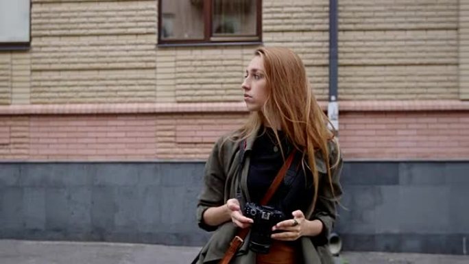 一位女旅游摄影师走在街上拍照。穿着时尚的模特慢动作