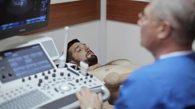 放射科医生用超声检查男性患者的腹部。