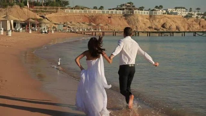 幸福的新婚夫妇在冲浪上奔跑。在埃及度蜜月。