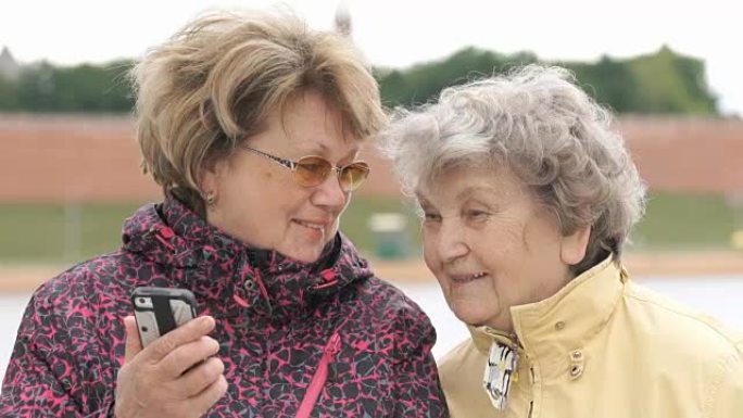 女人用手机向老妇人展示照片