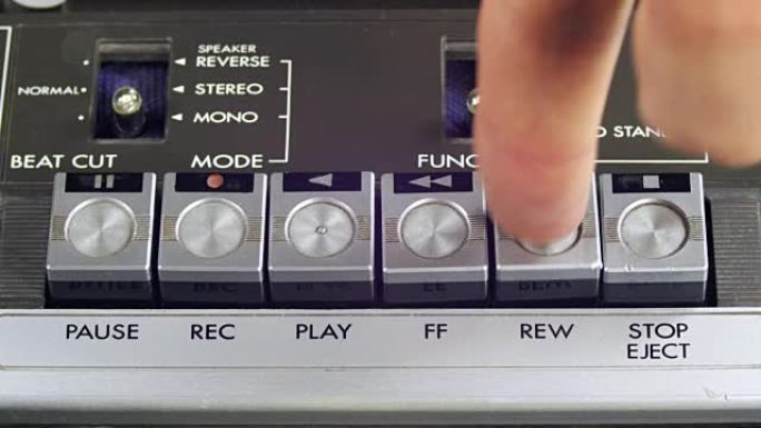 手指按播放，停止，前进，倒带，暂停和记录控制按钮的磁带播放机