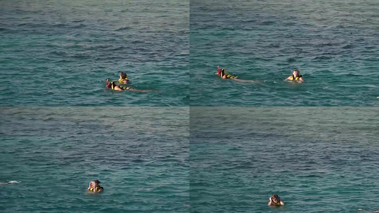 一名身穿救生衣的年轻女子戴上口罩，在水下看着