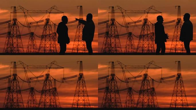 在能源变电站检查期间，两名戴着安全帽的工程师在夕阳红时大力讨论一些事情。
