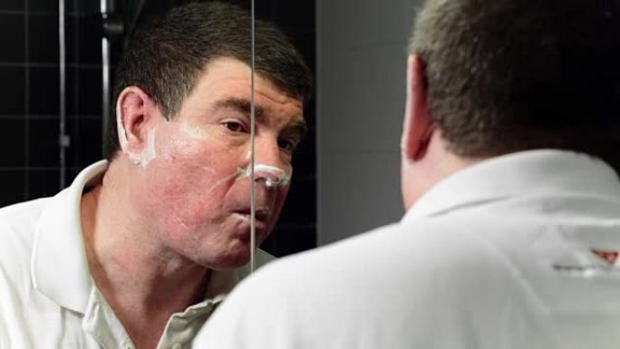人在镜子前刮胡子，被割伤了