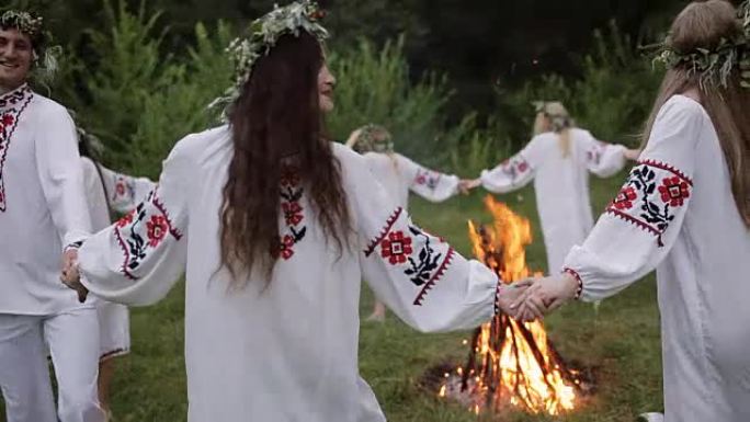 仲夏。穿着斯拉夫衣服的年轻人在仲夏围着火转。。