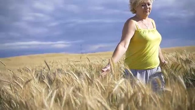 女人走在大麦的金色田野里，微笑着，慢动作