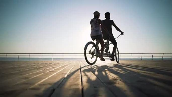 一对混血夫妇在海边户外骑双人自行车的肖像，