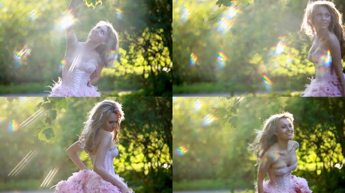 穿着粉色优雅连衣裙的年轻性感金发女孩在树林里跳舞