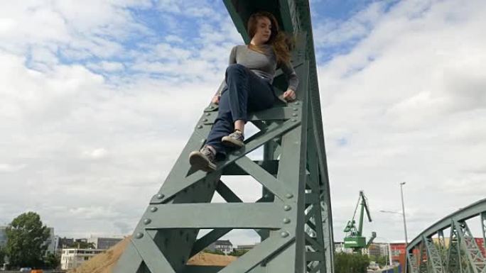 年轻女子坐在主河上的桥梁上