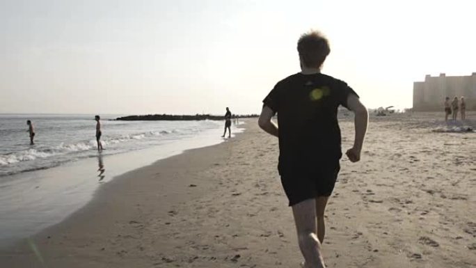 男子在日落时在海滩上奔跑240 fps慢动作