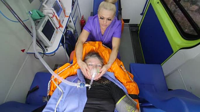 护理人员在救护车上戴着氧气面罩抱着病人的头