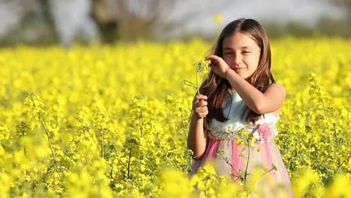 快乐美丽的年轻女孩在乡下的油菜场玩耍