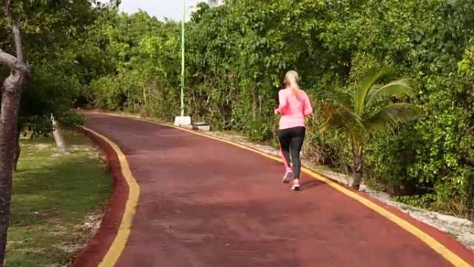 健身女性在夏季公园跑步。看着心率监测器，慢慢慢跑