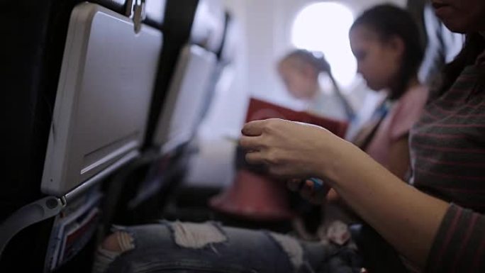 家人在飞机上度假，时间通过杂志和智能手机