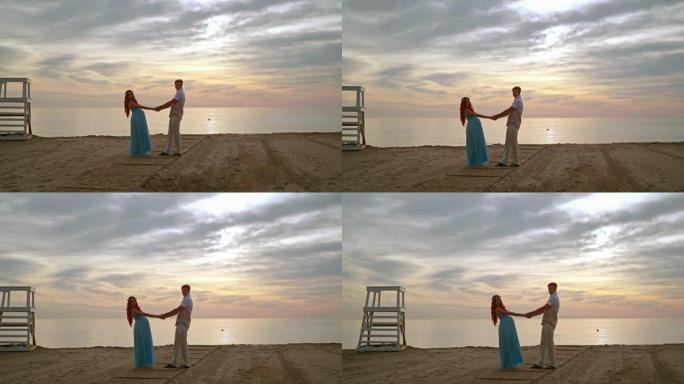 男人和女人在海边牵手。怀孕夫妇摆姿势拍照