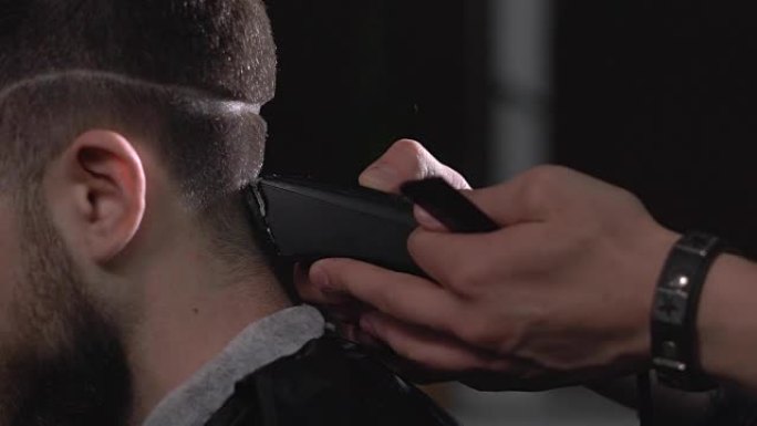 无法识别的理发师在沙龙的顾客头上应用修剪器