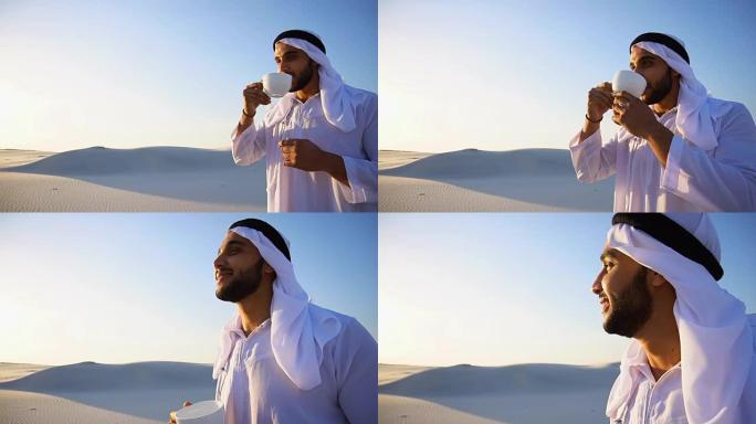 年轻英俊的阿拉伯酋长的肖像，他喝着咖啡，站在沙漠中，对着蓝天