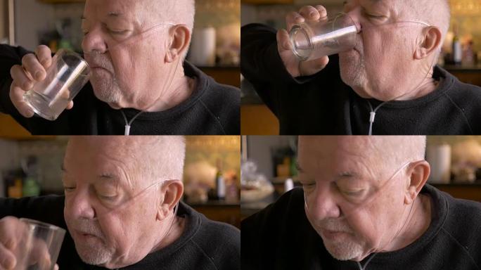 衰老的婴儿潮一代老人戴着氧气面罩从玻璃杯中喝酒