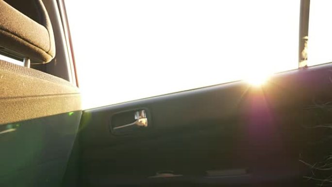 小女孩，无聊在车里。太阳耀斑。车窗上的日落灯。强风吹拂着头发。