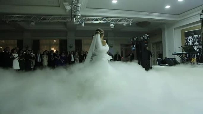 优雅的餐厅里有美妙的婚礼派对，光线和氛围都很棒。婚礼情侣在白色烟雾中跳舞第一支舞。慢动作镜头