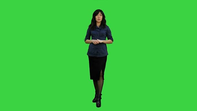 年轻迷人的亚洲女性对着镜头说话，在绿屏上展示一些东西，色度键