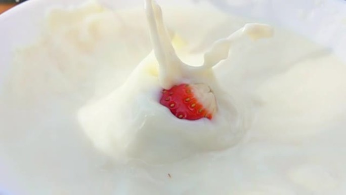 一半的草莓掉在一个装有奶油的碗里