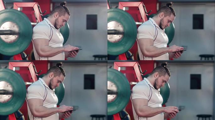 肌肉发达的人在锻炼之间在健身房使用电话