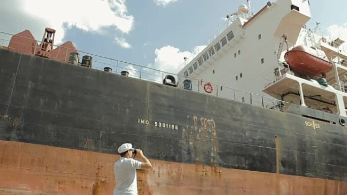 船长在一艘大船附近透过双筒望远镜看