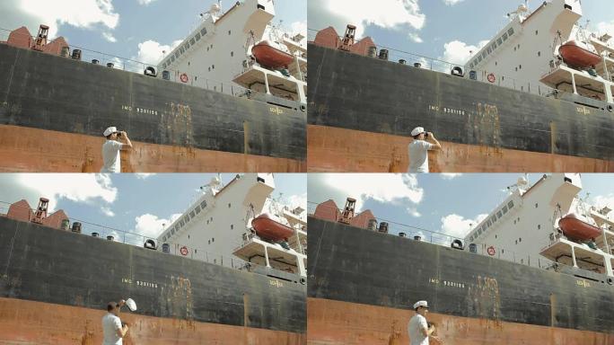 船长在一艘大船附近透过双筒望远镜看