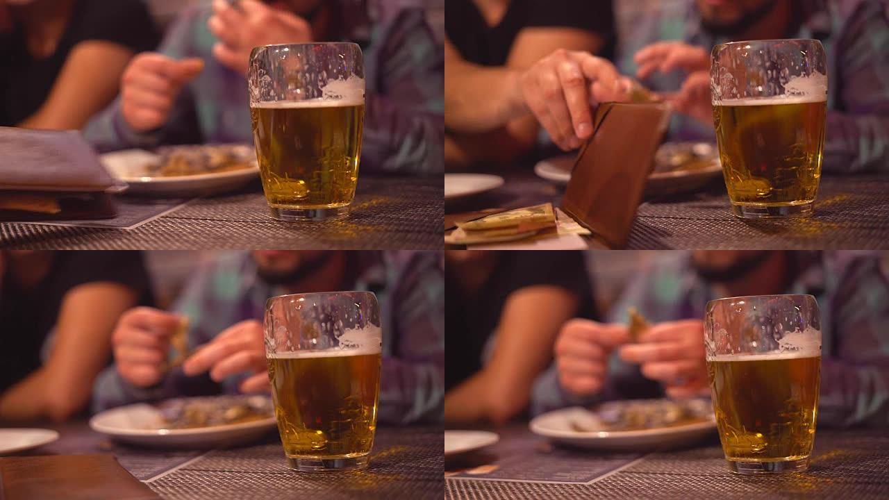 一个年轻人正在dluzyami的酒吧里喝啤酒。淡啤酒泡沫特写。在后台，这家伙有卡佩林。手中的油炸开胃