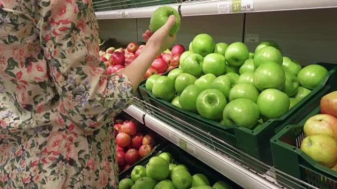 孕妇在杂货店挑选和闻到青苹果