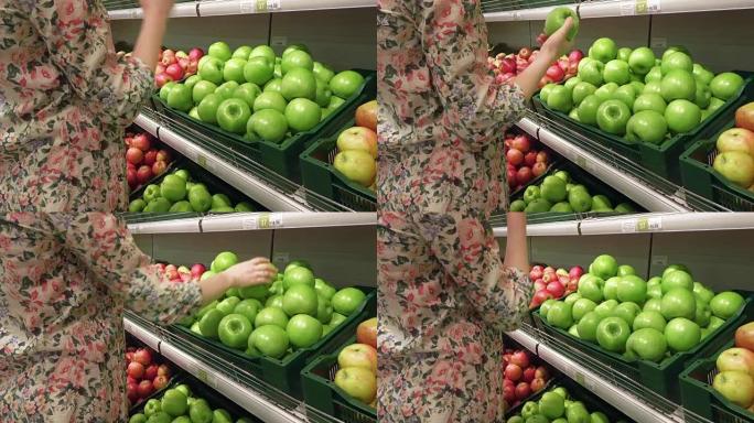 孕妇在杂货店挑选和闻到青苹果