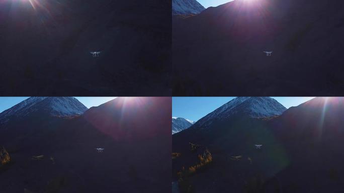 无人机在峡谷中飞行，在空中射击。一架白色的大型四旋翼飞行器或无人驾驶飞机在山上的山峰之间飞行。旋转飞