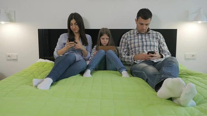 年轻的家庭躺在一张大床上，使用小玩意