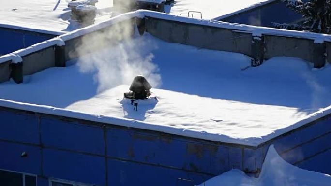 冬季背景一座现代建筑的屋顶被雪覆盖，烟囱冒出浓烟，