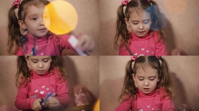 可爱的小女孩，用剪刀剪纸在圣诞花环的光芒中剪纸