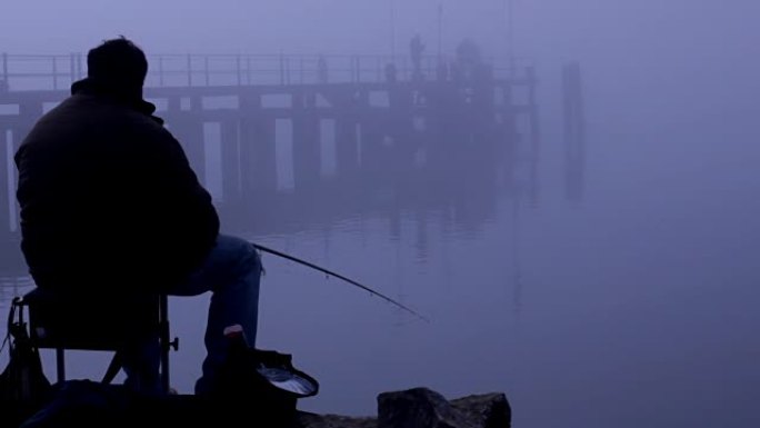坐在桥上钓鱼的人的剪影