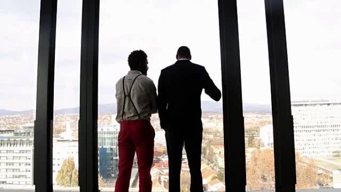 两个商人透过窗户看着城市