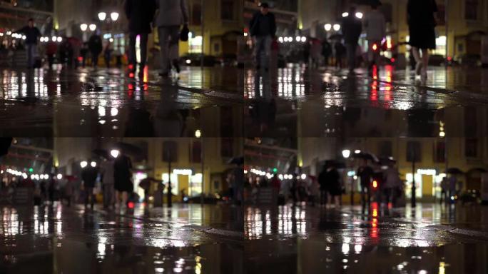 下雨的傍晚，雨滴落在路灯照亮的彩色沥青上。面目全非的人打着雨伞，用红绿灯过马路。美丽多彩的博克。天气