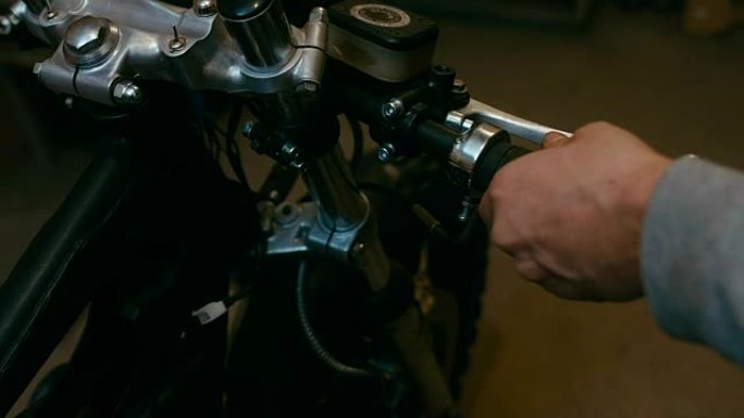 年轻的高加索男性机械师在车库里组装一辆定制的咖啡馆赛车摩托车