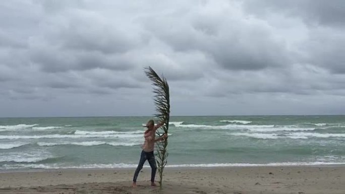 女人在海滩上拿着棕榈枝